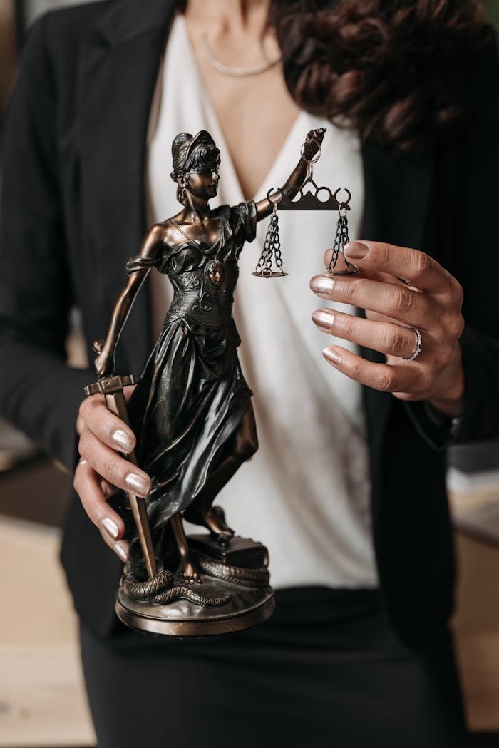 Home Close-up of Lady Justice statuette held by a lawyer, symbolizing law and justice.